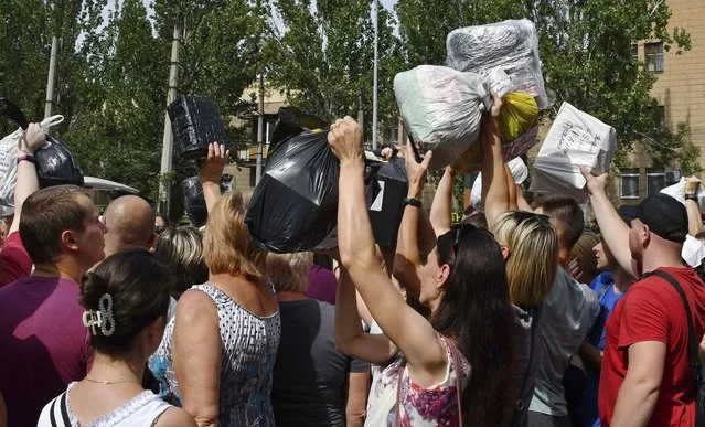 Local residents, many of whom fled the war, gather to hand out donated items such as medicines, clothes, and personal belongings to their relatives on the territories occupied by Russia, in Zaporizhzhia, Ukraine, Sunday, August 14, 2022. Volunteers transport these items across the frontline and distribute them to addresses at their own risk. (Photo by Andriy Andriyenko/AP Photo)