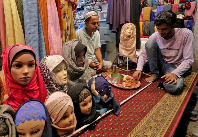 Muslim shopkeepers selling Hijabs have their Iftar meals during the fasting month of Ramadan in a street in Mumbai, India, April 7, 2022. (Photo by Niharika Kulkarni/Reuters)
