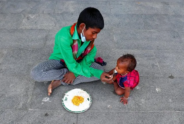 A homeless boy feeds his sister inside a sports complex turned into a shelter, during a 21-day nationwide lockdown to slow the spread of the coronavirus disease (COVID-19), in New Delhi, India, April 4, 2020. (Photo by Adnan Abidi/Reuters)