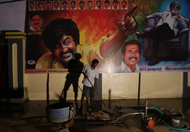 A laborer work to remove water from an overflowing tank next to the posters displaying pictures of Indian actor Rajinikanth at a theatre on the eve of release of his new movie “Kabali” in Chennai, India, Thursday, July 21, 2016. (Photo by Aijaz Rahi/AP Photo)