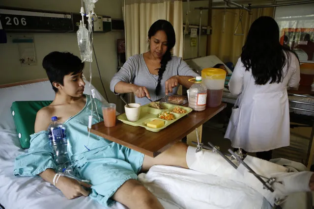 A 13-year-old boy from Iztapalapa, who along with his sister was seriously injured by a collapsing wall in last week's earthquake, is fed by his mother as he recuperates at the Magdalena de las Salinas trauma hospital, accompanied by their father, in Mexico City, Wednesday, September 27, 2017. The family rushed out of their home when the quake started, only to have a six-foot (two meter) perimeter wall fall on the children. The girl’s pelvis was crushed, her liver damaged and she had internal bleeding. The son had an exposed fracture of his leg, with the bone poking though and blood spurting out. (Photo by Rebecca Blackwell/AP Photo)