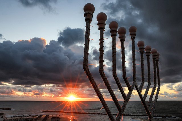 The sun sets over the Mediterranean sea as a nine-branched Hanukkah menorah (Hanukkiah) is pictured by the coast in Netanya on December 31, 2024. (Photo by Jack Guez/AFP Photo)