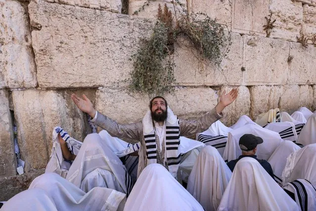 Jewish men, wearing traditional Jewish prayer shawls known as Tallit, perform the annual Cohanim prayer (priest's blessing) during the holiday of Sukkot, or the Feast of the Tabernacles, at the Western Wall in the old city of Jerusalem on October 12, 2022. Thousands of Jews annually make the pilgrimage to Jerusalem during the week-long holiday of Sukkot, which commemorates the desert wanderings of the Israelites after their exodus from Egypt according to biblical tradition, and the gathering of the harvest. (Photo by Menahem Kahana/AFP Photo)