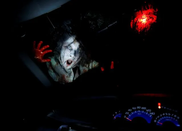 An actor dressed as a zombie performs during a drive-in haunted house show, performed by Kowagarasetai (Scare Squad), for people inside a car in order to maintain social distancing amid the spread of the coronavirus disease (COVID-19), at a garage in Tokyo, Japan on July 3, 2020. (Photo by Issei Kato/Reuters)