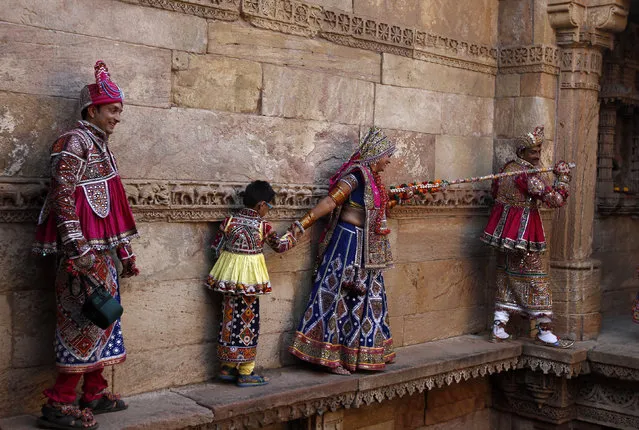 Performers dressed in traditional attire walk on a ledge before taking part in rehearsals for the “garba” dance ahead of the Navratri festival at Adalaj Stepwell, a five level octagonal step-well complex built in the 15th century, in Ahmedabad September 21, 2014. (Photo by Amit Dave/Reuters)