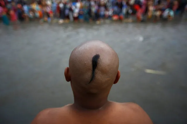 A devotees with a shaved head stands along the bank of Bagmati River while performing rituals in memory of his deceased father during Kuse Aunse (Father's Day) at Gokarna Temple in Kathmandu, Nepal September 1, 2016. Hindus all over the country, whose fathers have passed away, come to the temple for worship, holy dips, and to present offerings on this occasion. (Photo by Navesh Chitrakar/Reuters)