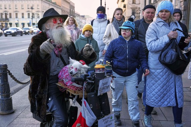 A man with a dog makes money entertaining pedestrians in St. Petersburg, Russia, Thursday, March 27, 2025. (Photo by Dmitri Lovetsky/AP Photo)