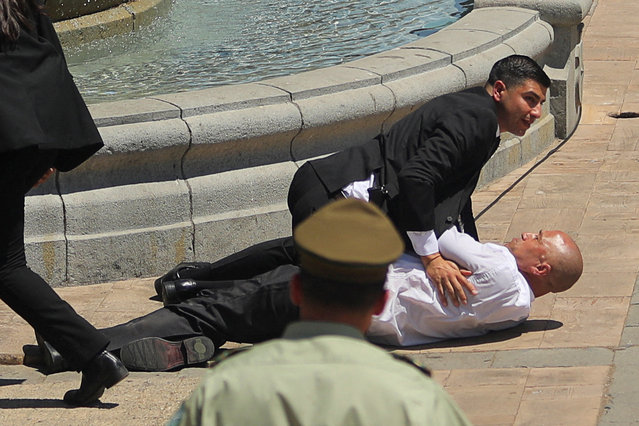 A Carabineros de Chile police officer detains a man on the ground, who tried to approach Chile's President Gabriel Boric with a briefcase, during a funeral event for Chile's former President Sebastian Pinera, at the presidential palace La Moneda in Santiago, Chile, on February 9, 2024. (Photo by Pablo Sanhueza/Reuters)