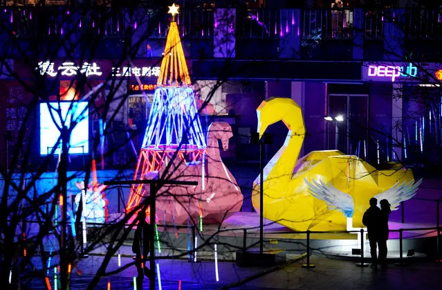 People stand next to Christmas decorations in Beijing's Sanlitun area, China December 19, 2017. (Photo by Jason Lee/Reuters)
