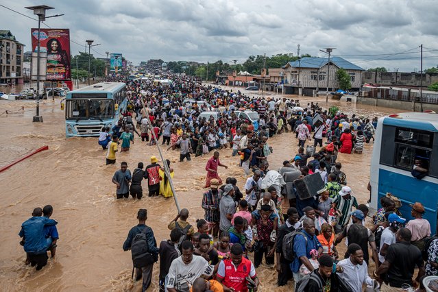 Residents wade through murky floodwaters following heavy rains in the Ndjili district of Kinshasa on April 6, 2025. Heavy downpours in the Democratic Republic of Congo's capital Kinshasa have left around 30 people dead while wrecking havoc in the central African megacity, an official told AFP on April 6, 2025.After the rain poured down overnight from Friday to Saturday, the rising water levels devastated several outlying and impoverished suburbs of the metropolis of some 17 million people. (Photo by Hardy Bope/AFP Photo)