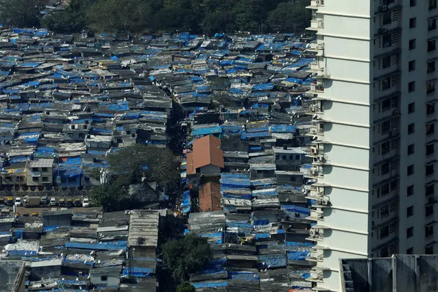 A high rise residential building is seen next to a slum in Mumbai, India, December 20, 2017. (Photo by Danish Siddiqui/Reuters)