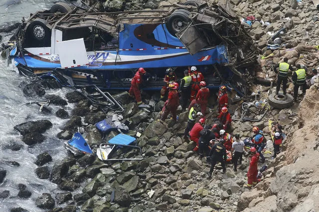 EDS NOTE GRAPHIC CONTENT - In this photo provided by the government news agency Andina, firemen recover bodies from a bus that fell off a cliff after it was hit by a tractor-trailer rig, in Pasamayo, Peru, Tuesday, Jan 2, 2018. A Peruvian police official says at least 25 people died, and that there were more than 50 people on the bus. (Vidal Tarky, Andina News Agency via AP)