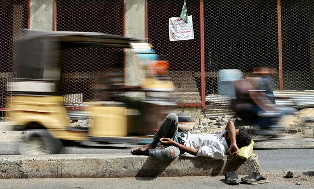 A man rests on the concrete divider of a road in Karachi on May 5, 2025. (Photo by Asif Hassan/AFP Photo)
