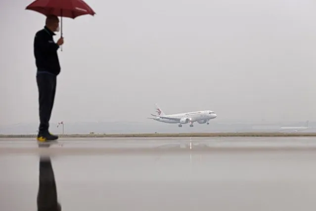 A man watches a Commercial Aircraft Corp of China (COMAC) C919 aircraft, China's first domestically produced large passenger jet, landing at Hongqiao International Airport after it is formally handed over to China Eastern Airlines in Shanghai on December 9, 2022. (Photo by AFP Photo/China Stringer Network)