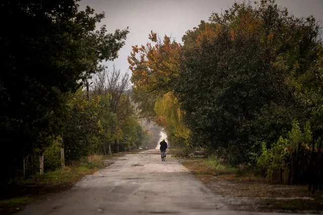 A man rides bicycle along a road near Mykolaiv, Sunday, October 23, 2022. (Photo by Emilio Morenatti/AP Photo)