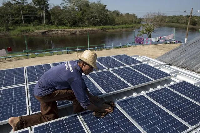 Francisco da Silva Vale, 61, cleans solar panels which power ice machines at Vila Nova do Amana community in the Sustainable Development Reserve, in Amazonas state, Brazil, September 22, 2015. (Photo by Bruno Kelly/Reuters)