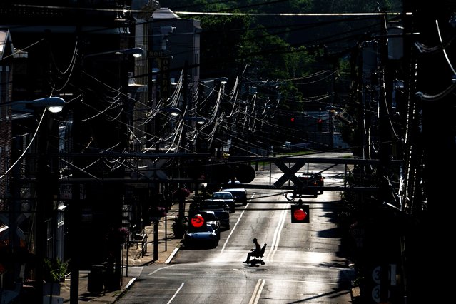 A man in an electric wheelchair crosses Pike Street in the sweltering heat in downtown Cynthiana, Ky., Monday, June 23, 2025. (Photo by Michael Swensen/AP Photo)