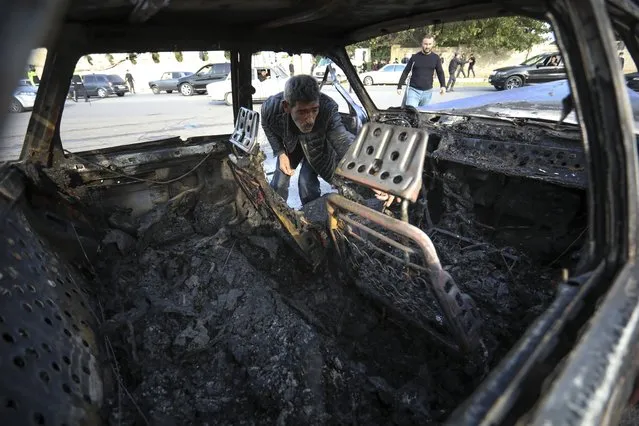 A man looks in a burnt out car after multiple rocket system shelling by Armenian forces in Barda, Azerbaijan, Wednesday, October 28, 2020. The Azerbaijani Defense Ministry rejected all the accusations and in turn accused Armenian forces of using the Smerch multiple rocket system to fire at the Azerbaijani towns of Terter and Barda. The strike on Barda killed more than 20 people and wounded 60, Azerbaijani officials said. (Photo by Aziz Karimov/AP Photo)