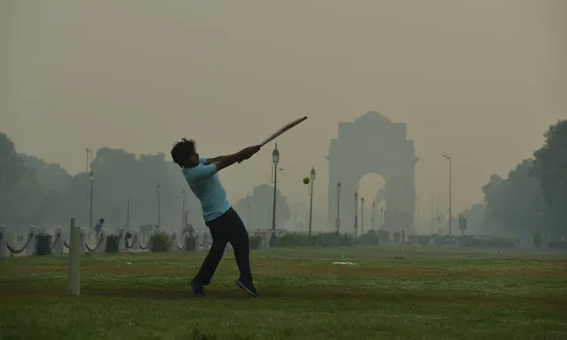 A boy Playing Cricket in Lawn of India Gate during smoggy morning as India Gate in the backdrop shrouded with smog in the early morning October 26, 2020. (Photo by Pradeep Gaur/Rex Features/Shutterstock)