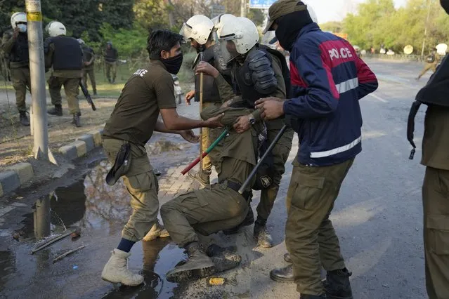 Police officers help their colleague injured in the clashes with the supporters of Pakistan's former Prime Minister Imran Khan, in Lahore, Pakistan, Wednesday, March 8, 2023. (Photo by K.M. Chaudary/AP Photo)