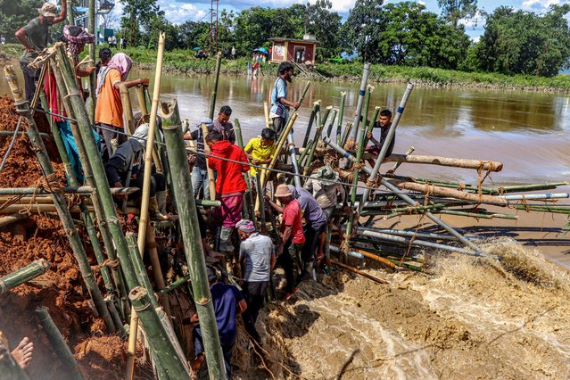 Local residents construct a temporary barrier using bamboo and poles to block a breach along the riverbank after heavy monsoon rains in Wangoi, Imphal West in India's northeastern state of Manipur on September 17, 2025. (Photo by AFP Photo/Stringer)