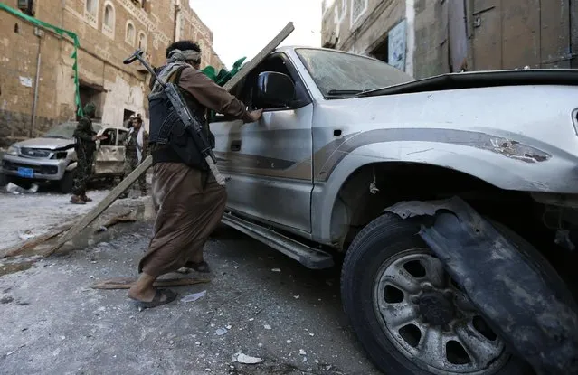 A Shi'ite Houthi militant checks a damaged car at the site of a bomb explosion in Sanaa December 23, 2014. (Photo by Khaled Abdullah/Reuters)