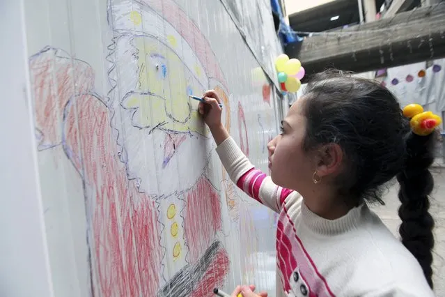 A displaced Iraqi Christian girl who fled from Islamic State militants in Mosul, draws a picture of Santa Claus at a mall still under construction, used as a refugee camp in Arbil December 24, 2014. (Photo by Azad Lashkari/Reuters)