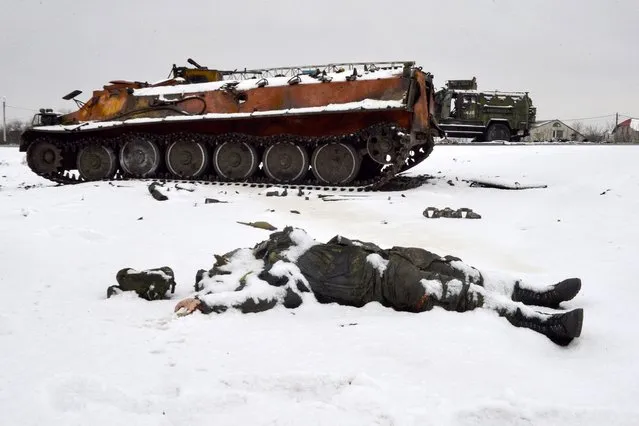 The body of a Russian serviceman lies near destroyed Russian military vehicles on the roadside on the outskirts of Kharkiv on February 26, 2022, following the Russian invasion of Ukraine. Ukrainian forces repulsed a Russian attack on Kyiv but “sabotage groups” infiltrated the capital, officials said on February 26, as Ukraine reported 198 civilian deaths, including children, following Russia's invasion. A defiant Ukrainian President Volodymyr Zelensky vowed his pro-Western country would never give in to the Kremlin even as Russia said it had fired cruise missiles at military targets. (Photo by Sergey Bobok/AFP Photo)