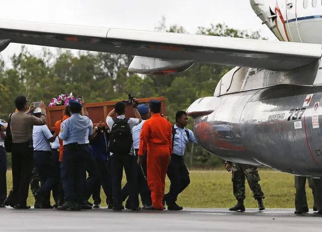 Air Force soldiers carry a coffin containing the body of a passenger onboard AirAsia flight QZ8501 at Iskandar airbase in Pangkalan Bun district, Indonesia, to be transported to Surabaya, December 31, 2014. A body recovered on Wednesday from the crashed AirAsia plane was wearing a life jacket, an official with Indonesia's search and rescue agency said, raising questions about how the disaster unfolded. (Photo by Reuters/Beawiharta)