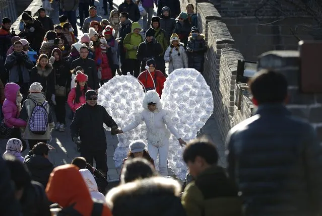 Chinese artist Kong Ning wearing a costume symbolizing a butterfly, which is decorated with 365 masks on its wings to represent the number of days in a year, is assisted by her friend as she makes her way during her performance art at the Badaling section of the Great Wall on the outskirts of Beijing January 1, 2015. (Photo by Kim Kyung-Hoon/Reuters)