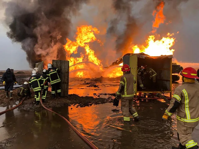Firefighters from the Iraqi state-owned North Oil Company put out a fire at an oil well in the northern Khabbaz oil field, about 20 kilometres (12 miles) southwest of Kirkuk in northern Iraq on December 16, 2020. Iraqi authorities had blamed the Islamic State group (IS) for the fires which had been raging for a week. IS has previously set oil fields aflame in Iraq. (Photo by Marwan Ibrahim/AFP Photo)