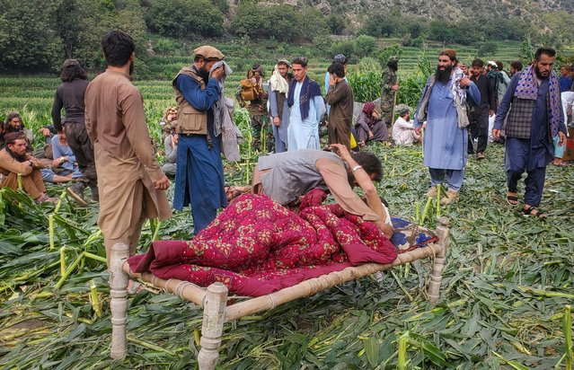 An Afghan man helps an injured person after a deadly magnitude-6 earthquake that struck Afghanistan around midnight, as others take refuge in a field in Dara Mazar, in Kunar province, Afghanistan, on September 1, 2025. (Photo by Reuters/Stringer)