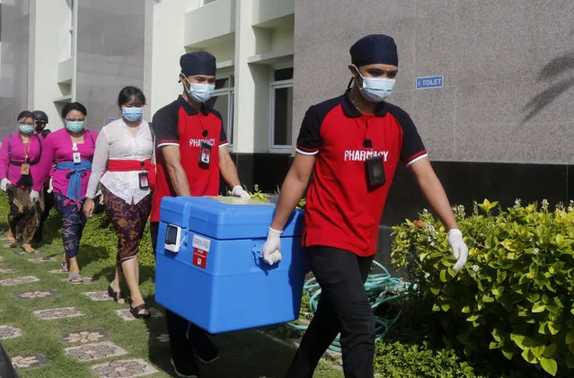 In this January 14, 2021, health workers carry COVID-19 vaccine during vaccination at a hospital in Bali, Indonesia. The global death toll from COVID-19 has topped 2 million. (Photo by Firdia Lisnawati/AP Photo/File)