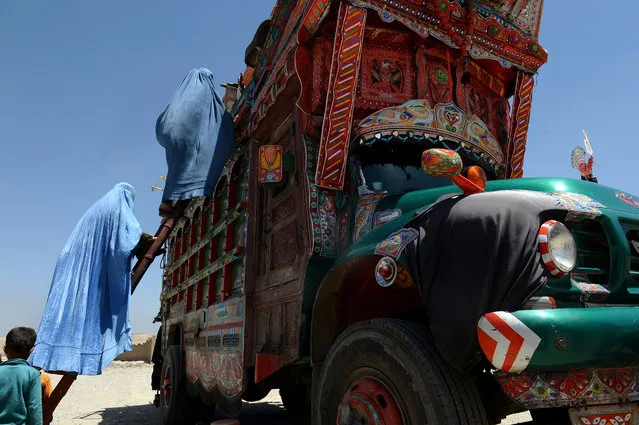 An Afghan refugee family climbs onto a truck at a United Nations High Commissioner for Refugees (UNHCR) camp in Kabul on June 20, 2013.  Scarred by decades of war, social problems, poverty and insecurities, millions of Afghans still live as refugees mainly in neighbouring Iran and Pakistan. (Photo by Shah Marai/AFP Photo)