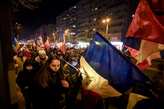 Protesters waving flags march after a deadly fire at a hospital treating COVID-19 patients in Bucharest, Romania, Saturday, January 30, 2021. (Photo by Andreea Alexandru/AP Photo)