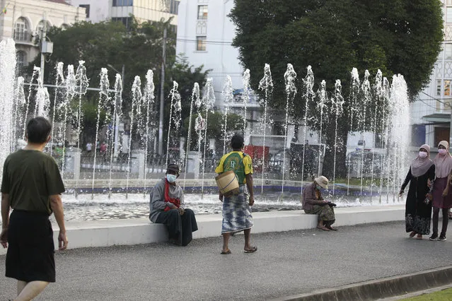 People walk next to a water fountain Monday, February 1, 2021 in Yangon, Myanmar. (Photo by Thein Zaw/AP Photo)
