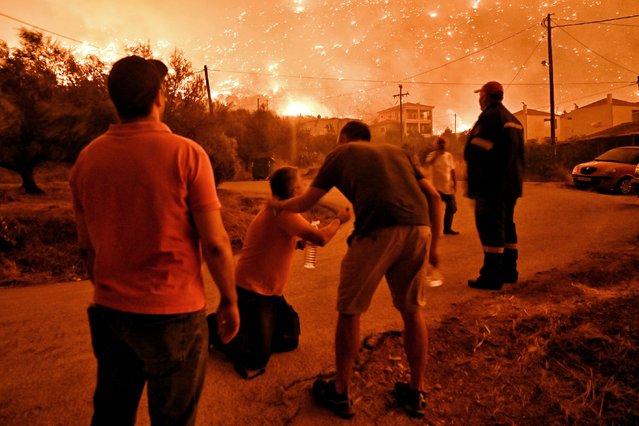 A resident reacts as a wildfire approaches the village of Ano Loutro as fanned by strong winds raged uncontrolled despite the attempts of hundreds of firefighters to stop it, some 131 kilometers (81 miles) west of Athens, Greece, in the region of Corinthia, late Sunday, September 29, 2024. (Photo by AP Photo/Stringer)