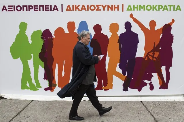 A man walks past a banner of opposition radical leftist Syriza party's election kiosk in Athens January 19, 2015. The words on the banner read, “Dignity, justice, democracy”. (Photo by Marko Djurica/Reuters)