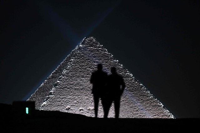 Models are silhoutted against the Pyramids at the Christian Dior fashion show at the Giza Pyramids Necropolis on the outskirts of the twin city of Egypt's capital on December 3, 2022. French fashion house Dior today held its first show at Egypt's ancient Giza pyramids, presenting its 2023 fall men's collection in the shadow of the of the millennia-old tombs. (Photo by Ahmed Hasan/AFP Photo)
