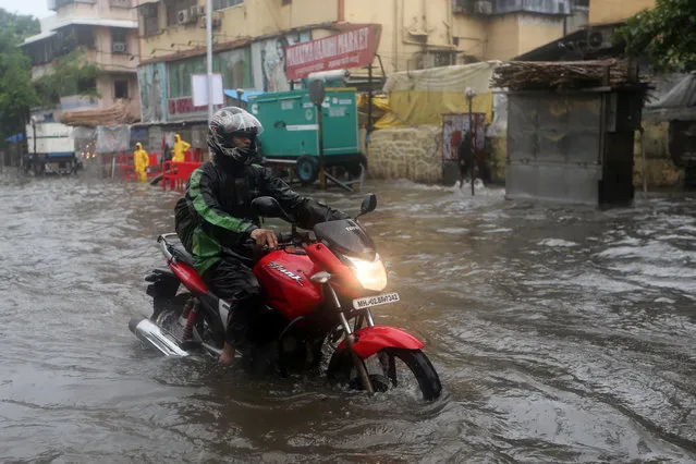 A man rides a motorcycle through a water-logged street after heavy rains in Mumbai June 25, 2018. (Photo by Francis Mascarenhas/Reuters)