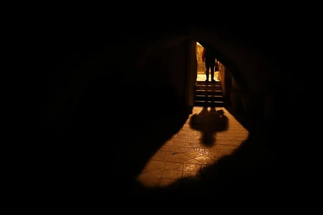 A man is silhouetted as he walks in an alley at night amid the coronavirus disease (COVID-19) crisis, in Jerusalem's Old City on November 25, 2020. (Photo by Ammar Awad/Reuters)