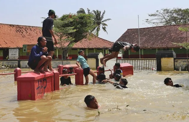 Indonesian youths play in the water during a flood in Bekasi, Indonesia, Monday, February 22, 2021. Thousands of residents are being evacuated on the outskirts of Indonesia's capital amid flooding after the Citarum River embankment broke, officials said Monday. (Photo by Achmad Ibrahim/AP Photo)