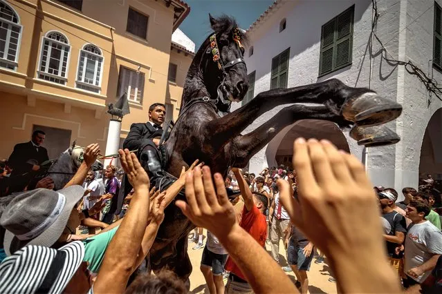 A “caixer” (horse rider) rears up on his horse surrounded by a cheering crowd during the jaleo prior to the “Jocs des Pla” (medieval tournament) during the traditional “Sant Joan” (Saint John) festival in Ciutadella de Menorca, Spain on June 24, 2023. (Photo by Matthias Oesterle/Rex Features/Shutterstock)