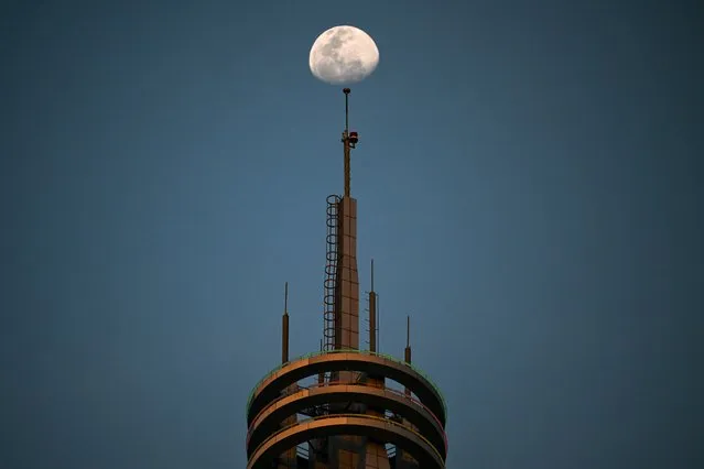 The moon is pictured above a building in Kuala Lumpur on May 31, 2023. (Photo by Mohd Rasfan/AFP Photo)