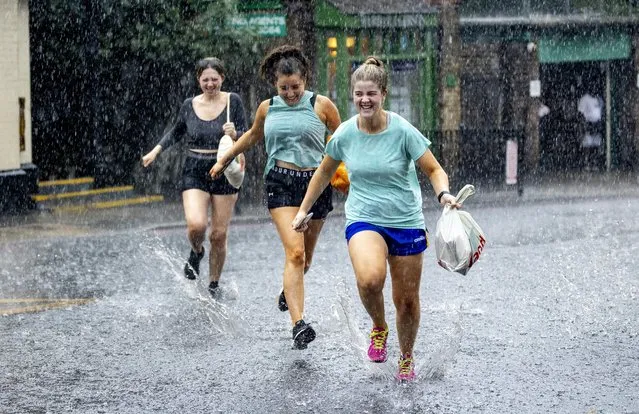 Three young women sprint for cover after getting caught but they were laughing with joy. Fun for some – not so much for others. Leaping over and into puddles. Torrential rain and lightning and thunder in North London Highgate on August 17, 2022. Storm drenched people out and created huge puddles for traffic People ran to escape. (Photo by Gavin Rodgers/Pixel8000)