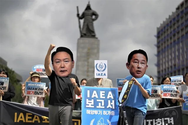 Members of civic groups wearing masks of Japanese Prime Minister Fumio Kishida, right, and South Korean President Yoon Suk Yeol pose during a rally to oppose Japanese government's decision to release treated radioactive water into the sea from the Fukushima nuclear power plant, in Seoul, South Korea, Wednesday, July 5, 2023. The letters read “Report of the IAEA”. (Photo by Lee Jin-man/AP Photo)