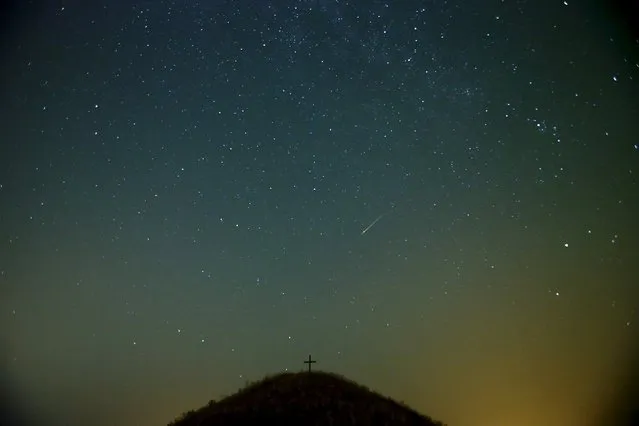 A meteor streaks across the sky over Leeberg hill during the Perseid meteor shower near Grossmugl in the early morning of August 13, 2015. (Photo by Heinz-Peter Bader/Reuters)