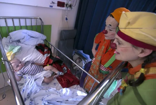 Belgian clowns Rondelle (C) and Bretzel (R) interact with six-month-old baby Lucas, who is hospitalized at the pediatric department of the Hopital Erasme at the Universite Libre de Bruxelles (ULB), in Brussels  February 10, 2015. (Photo by Yves Herman/Reuters)