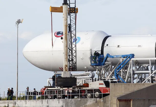 SpaceX workers examine the unmanned Falcon 9 rocket carrying NOAA's (National Oceanic and Atmospheric Administration) Deep Space Climate Observatory Satellite as it lays horizontally on launch complex 40 at the Cape Canaveral Air Force Station in Cape Canaveral, Florida February 9, 2015. (Photo by Scott Audette/Reuters)