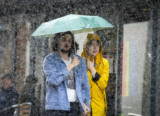 A couple shelter under an umbrella during a heavy downpour of rain in Belfast, Ireland on Monday, July 31, 2023. (Photo by Liam McBurney/PA Images via Getty Images)